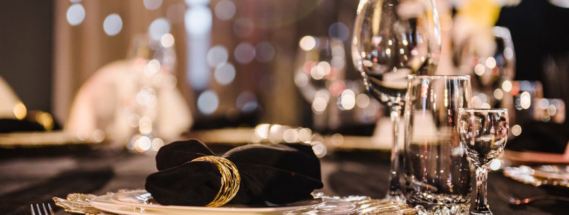 A premium event tablescape featuring black linen tablecloths and cloth napkins.