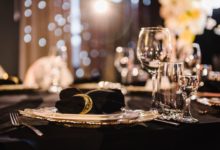 A premium event tablescape featuring black linen tablecloths and cloth napkins.