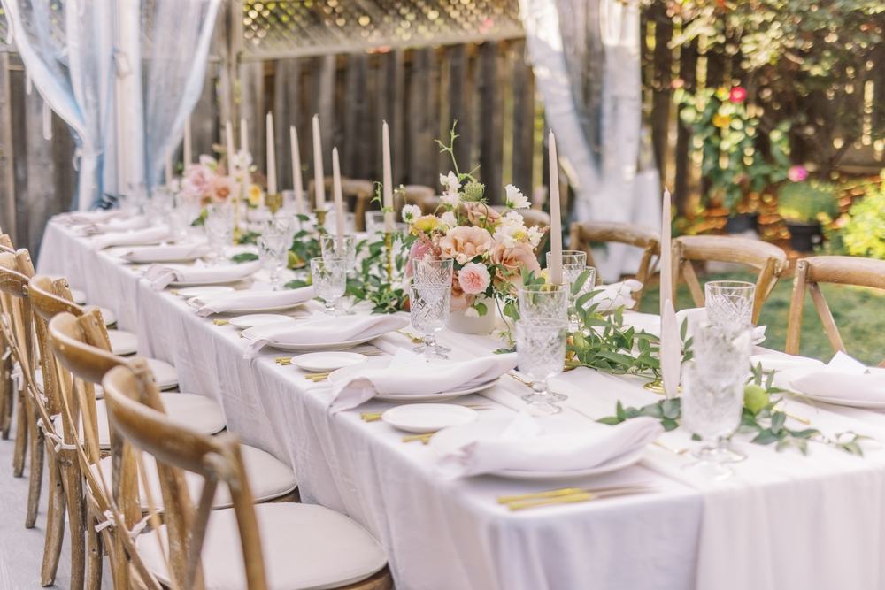 Fine white linens at an outdoor event with wooden chairs.