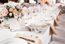 Formal table setting with white linens and tan napkins.