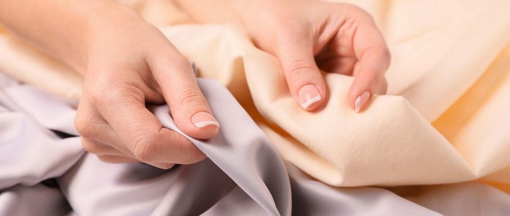 A party planner compares two different tablecloths, one gold and one silver, holding them side by side.