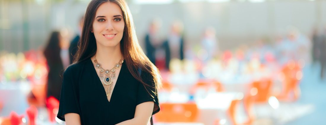 A wedding planner stands in front of her outdoor corporate event setup, complete with rented linens.